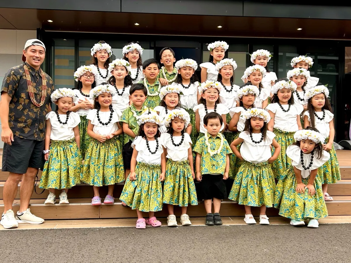 おそろいの衣装と花の冠をつけたフラキッズと田村さん